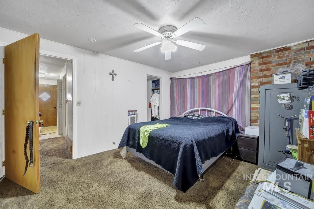 111 2nd Street Rupert, ID 83350 - Photo 11 of 45 Carpeted room featuring a ceiling fan with integrated lighting, a natural wood door, and a partial exposed brick wall