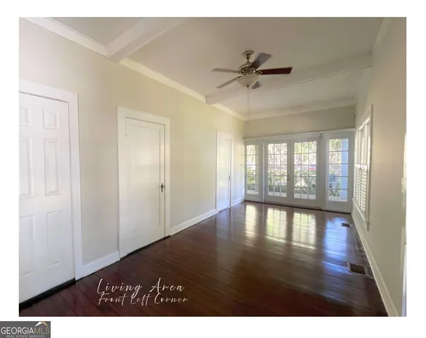 a view of an empty room with a window and wooden floor