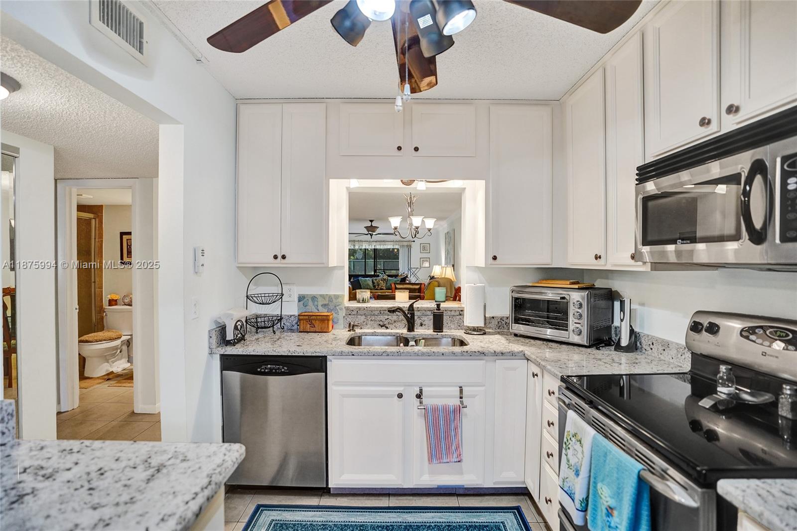 2975 Southwest 22nd Avenue, Unit 102 Delray Beach, FL 33445 - Photo 13 of 73 a kitchen with a sink stove and microwave