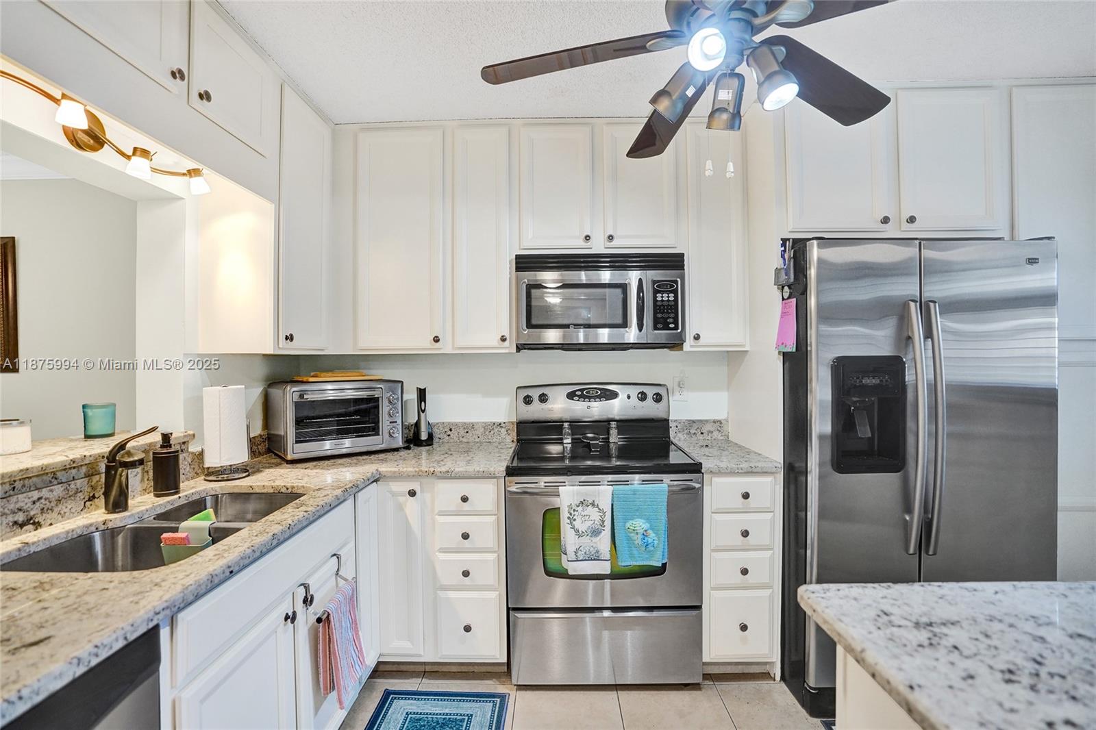 2975 Southwest 22nd Avenue, Unit 102 Delray Beach, FL 33445 - Photo 8 of 73 a kitchen with stainless steel appliances granite countertop a refrigerator a stove a sink and white cabinets