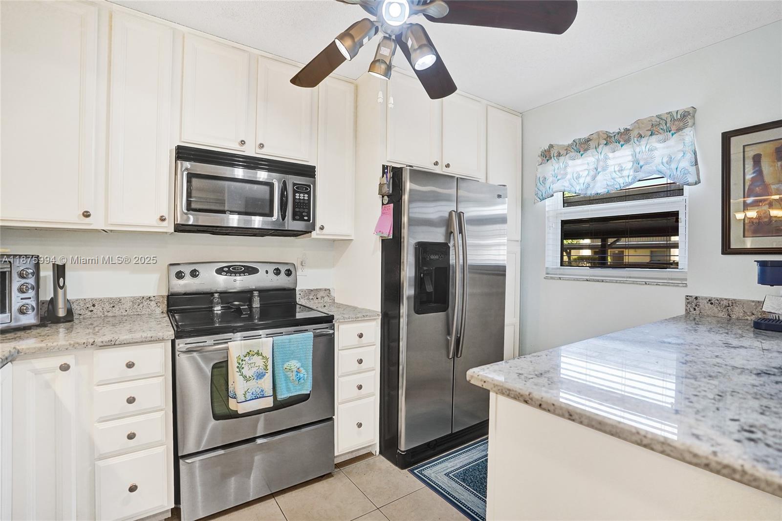 2975 Southwest 22nd Avenue, Unit 102 Delray Beach, FL 33445 - Photo 10 of 73 a kitchen with stainless steel appliances granite countertop a refrigerator a stove a microwave oven with white cabinets