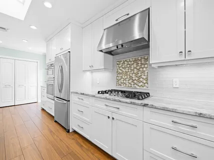 a kitchen with stainless steel appliances white cabinets and a wooden floor