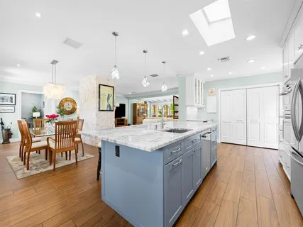 a large kitchen with stainless steel appliances kitchen island granite countertop a stove and a wooden floors