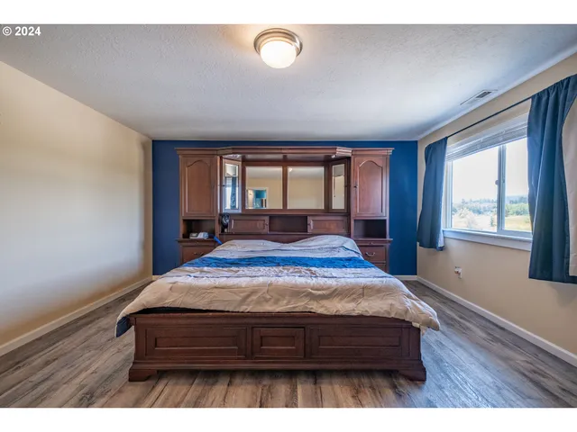 a bedroom with a bed window and wooden floor