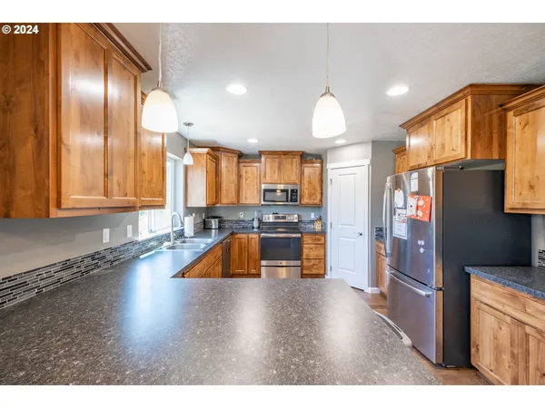 a kitchen with stainless steel appliances granite countertop a refrigerator a sink and a stove