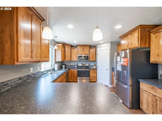 a kitchen with stainless steel appliances granite countertop a refrigerator a sink and a stove