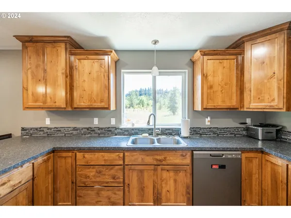 a kitchen with granite countertop a sink window and cabinets
