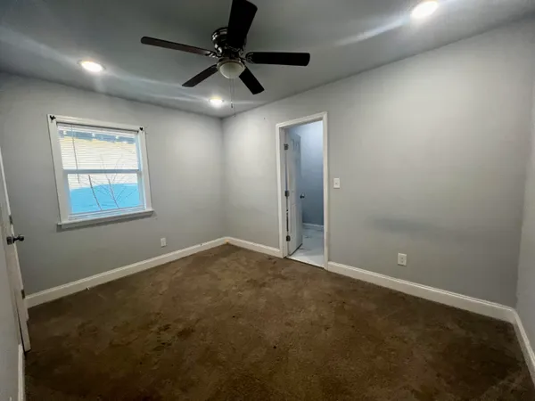 en empty room with windows and fan