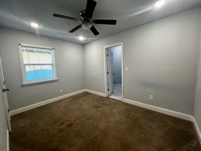 en empty room with windows and fan