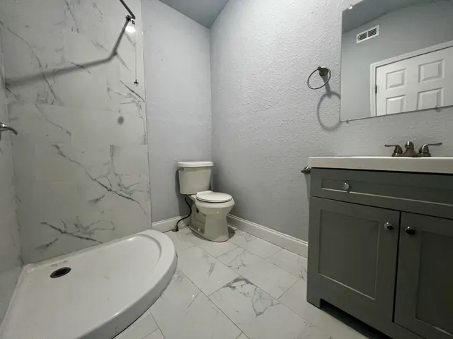 a bathroom with a sink a toilet and shower
