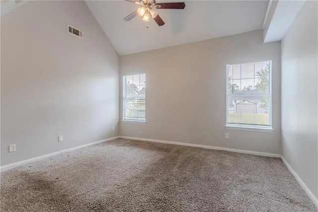 an empty room with windows and fan