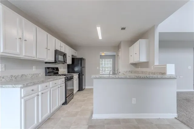 a kitchen with stainless steel appliances granite countertop a stove top oven a sink a refrigerator and white cabinets