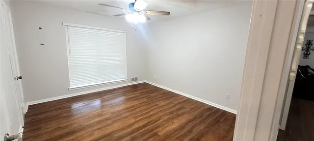 an empty room with wooden floor closet and windows