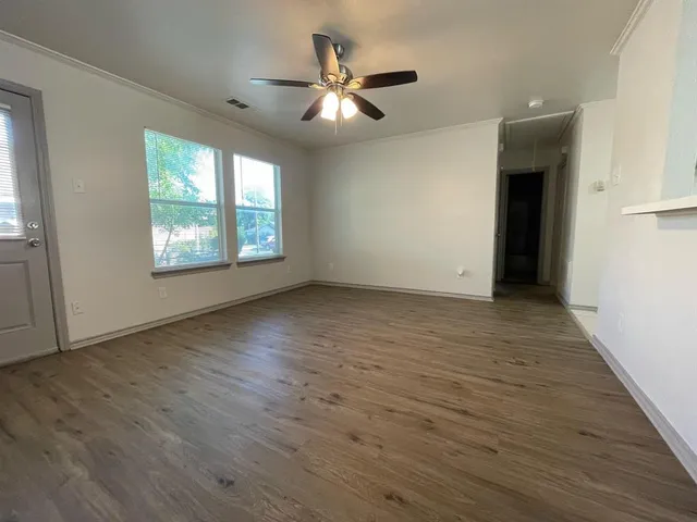 an empty room with wooden floor and windows