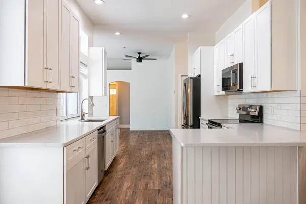 a kitchen with stainless steel appliances granite countertop a table chairs microwave and sink