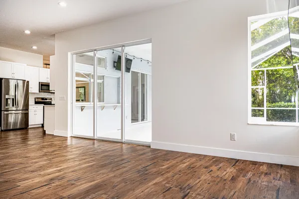 an empty room with wooden floor and windows