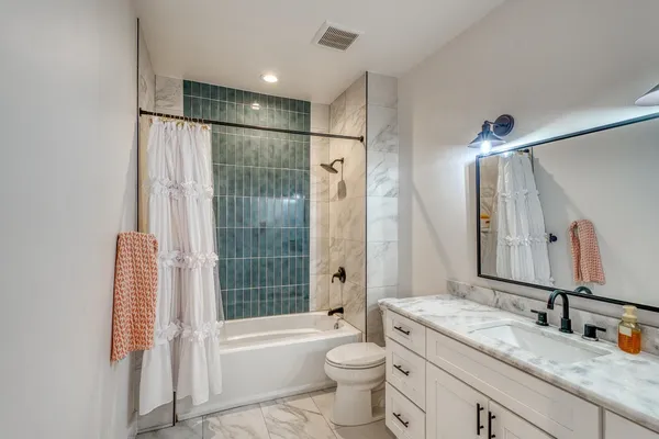 a bathroom with a granite countertop sink toilet tub and shower