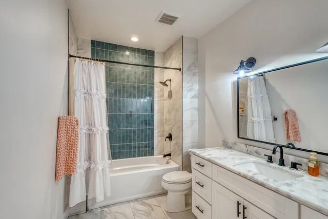 a bathroom with a granite countertop sink toilet tub and shower