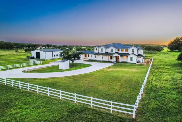 a view of a house with a big yard and large trees