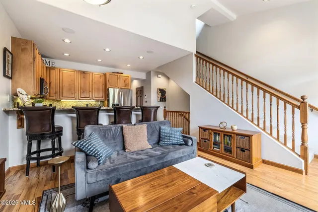 a living room with furniture kitchen view and a wooden floor
