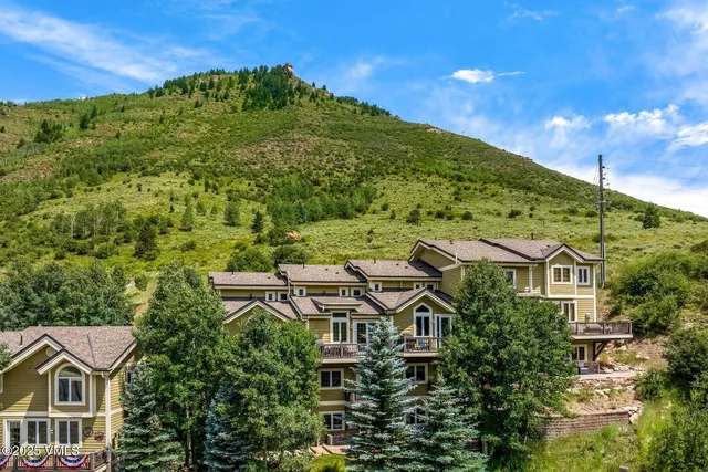 a view of a big house with a big yard and large trees