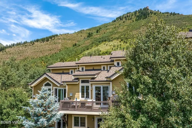 a view of a big house with a big yard plants and large trees