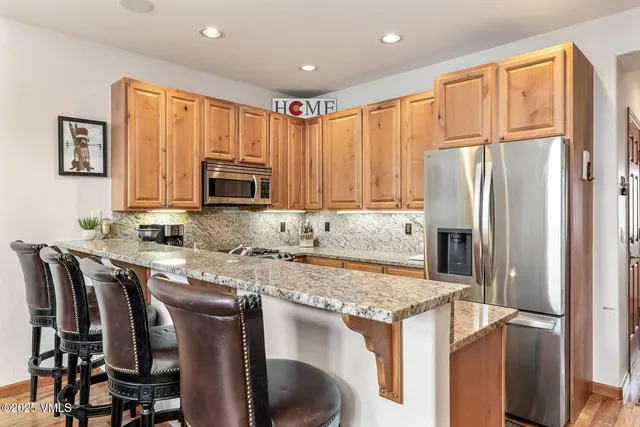 a kitchen with stainless steel appliances granite countertop a refrigerator a stove top oven a sink and dishwasher