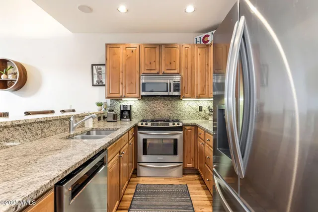 a kitchen with granite countertop a refrigerator stove and sink