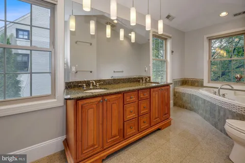 a bathroom with a granite countertop sink a mirror and a bathtub