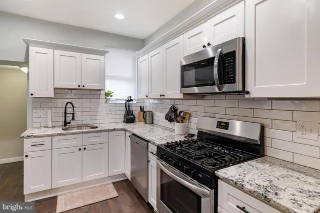 a kitchen with stainless steel appliances white cabinets granite counter tops and a window