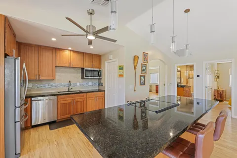 a large kitchen with kitchen island a large counter top space a sink stainless steel appliances and cabinets