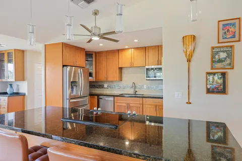 a kitchen with stainless steel appliances granite countertop a refrigerator a stove and a sink with granite countertops