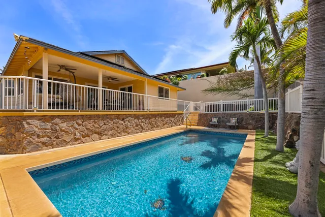 a view of swimming pool with lawn chairs and wooden fence