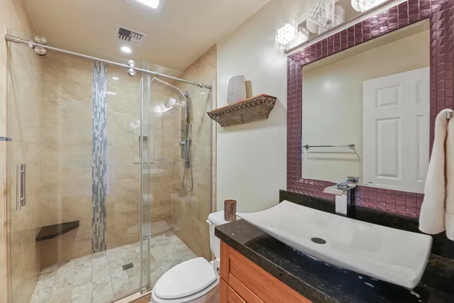 a bathroom with a granite countertop shower a sink and a toilet