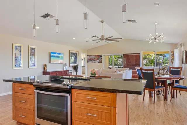 a kitchen with a stove a sink a dining table and chairs with wooden floor