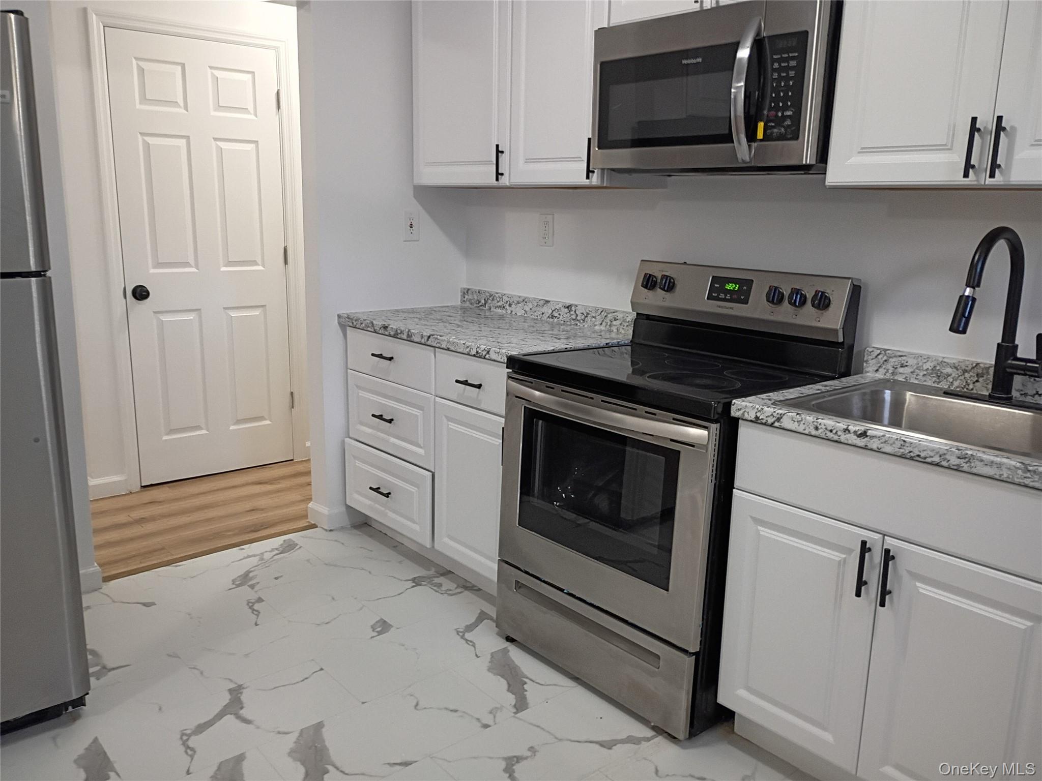 67 Albany Avenue, Unit A&B Flanders, NY 11901 - Photo 5 of 24 Kitchen with light marble finish flooring, stainless steel appliances, and white cabinets