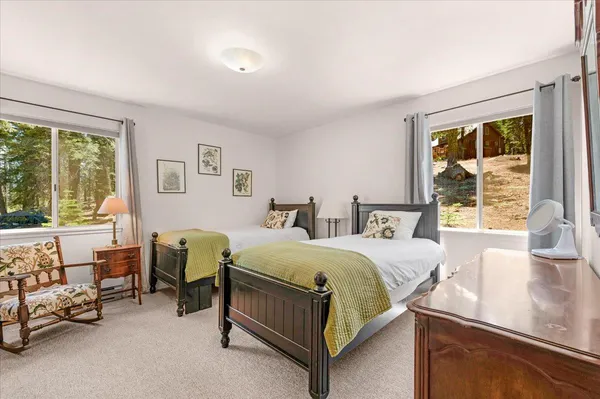 a spacious bedroom with a bed and a lamp on dresser