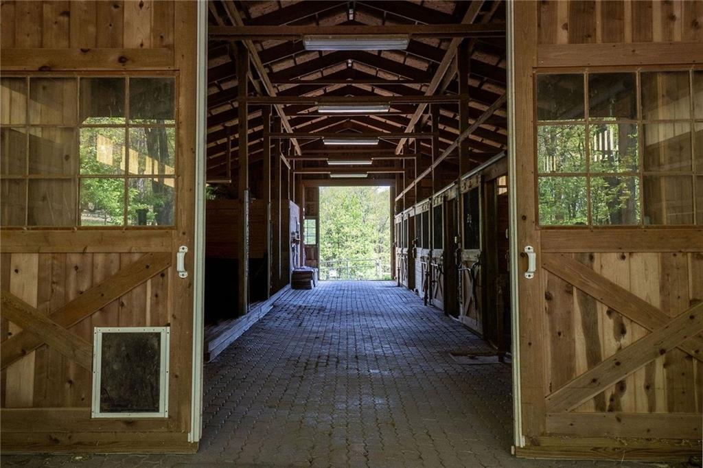 45 Stonedale Road Sewickley, PA 15143 - Photo 10 of 26 Inside the barn, a central aisle is flanked by well-appointed stalls with wood paneling, ideal for equestrian care and boarding.