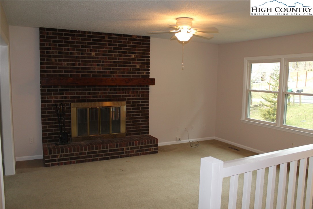 465 Highland Avenue Boone, NC 28607 - Photo 10 of 10 a view of a livingroom with a fireplace a ceiling fan and windows