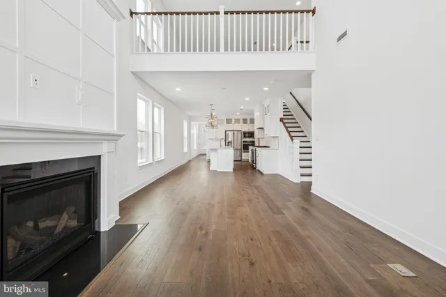 a view of an empty room with wooden floor fireplace and a window
