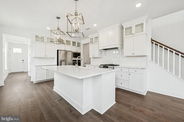 a kitchen with stainless steel appliances kitchen island hardwood floor sink and cabinets