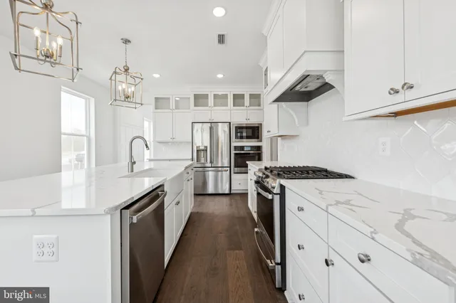 a kitchen with stainless steel appliances granite countertop a sink a stove a refrigerator and island with wooden floor