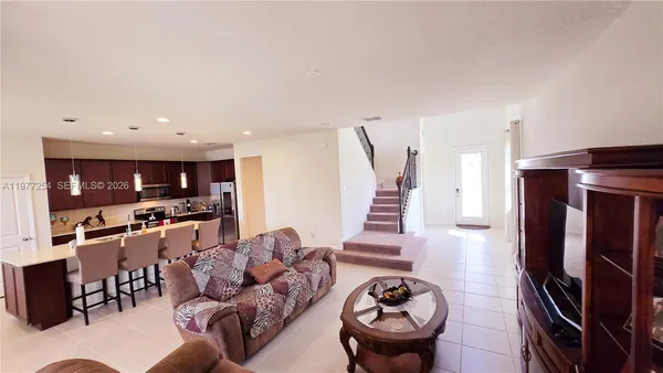 a living room with furniture a rug and kitchen view