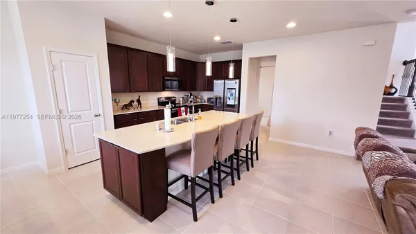 a kitchen with stainless steel appliances kitchen island granite countertop a refrigerator a sink a stove a dining table and chairs