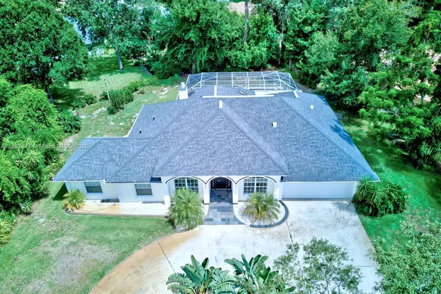 an aerial view of residential house with outdoor space and trees all around