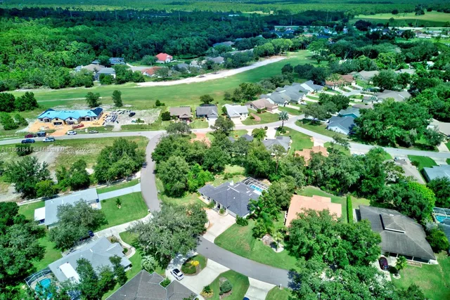 an aerial view of residential houses with outdoor space and trees all around