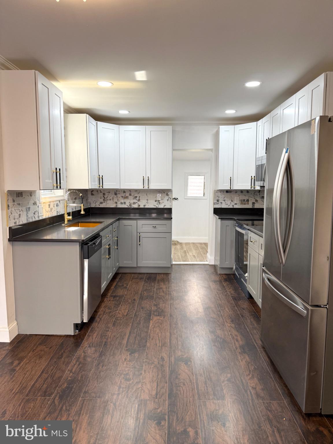 6824 Rodney Street Philadelphia, PA 19138 - Photo 2 of 28 a kitchen with stainless steel appliances granite countertop a stove a sink dishwasher a refrigerator and white cabinets with wooden floor