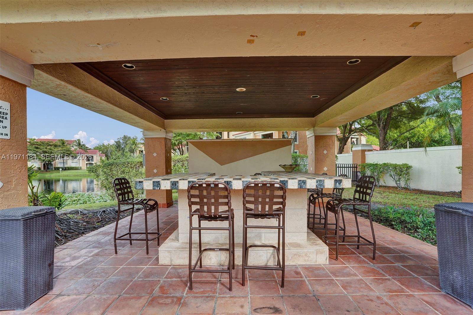 2061 Renaissance Boulevard, Unit 204 Miramar, FL 33025 - Photo 23 of 27 a view of a patio with a dining table and chairs with a wooden fence