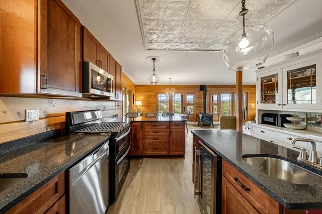 a kitchen with kitchen island granite countertop a sink stainless steel appliances wooden floor and cabinets