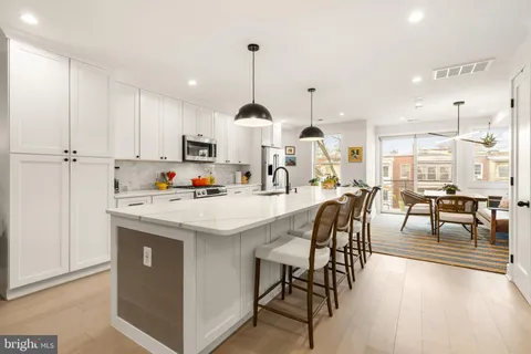 a kitchen with stainless steel appliances kitchen island granite countertop a table chairs and a refrigerator